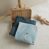 Dalmatian swaddle and navy blanket folded next to a toy and basket